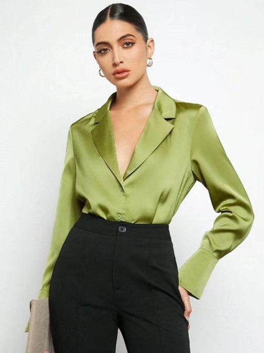 Woman wearing a green satin blouse and black pants against a white background