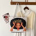 Tote bag with a design of a woman with a crown on a hanger with clothes in the background.