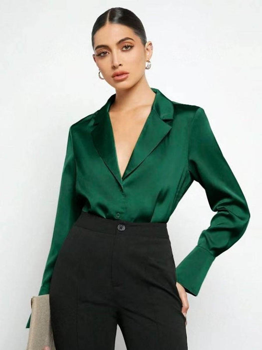 Woman wearing a green satin blouse and black pants against a white background