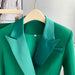 Green blazer on a hanger against a neutral background