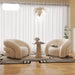 Modern living room with two cream-colored armchairs, a small table, and decorative elements.