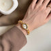 Gold wristwatch with a decorative face on a wrist, blurred background