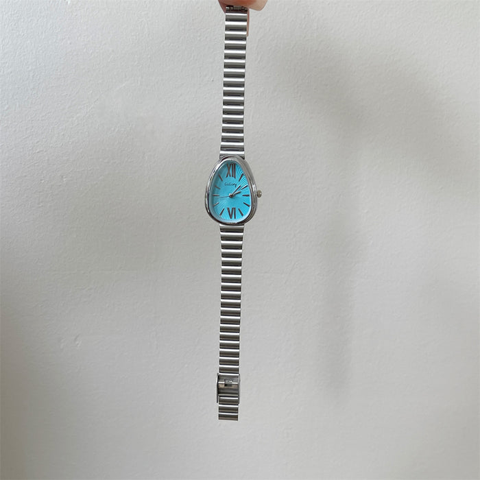 A vintage-style wristwatch with a silver-toned metal link bracelet and a bright turquoise blue oval dial, held by a hand against a plain off-white wall.