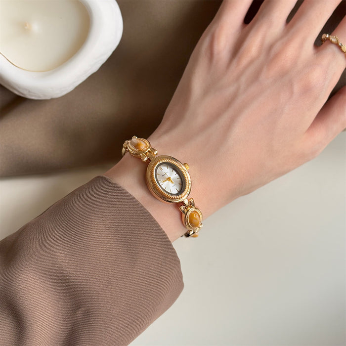 Gold wristwatch with a decorative face on a wrist, blurred background