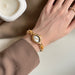 Gold wristwatch with a decorative face on a wrist, blurred background