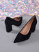 A pair of black pointed-toe high heels with block heels, shown on a gray surface with a sparkling multicolor backdrop.
