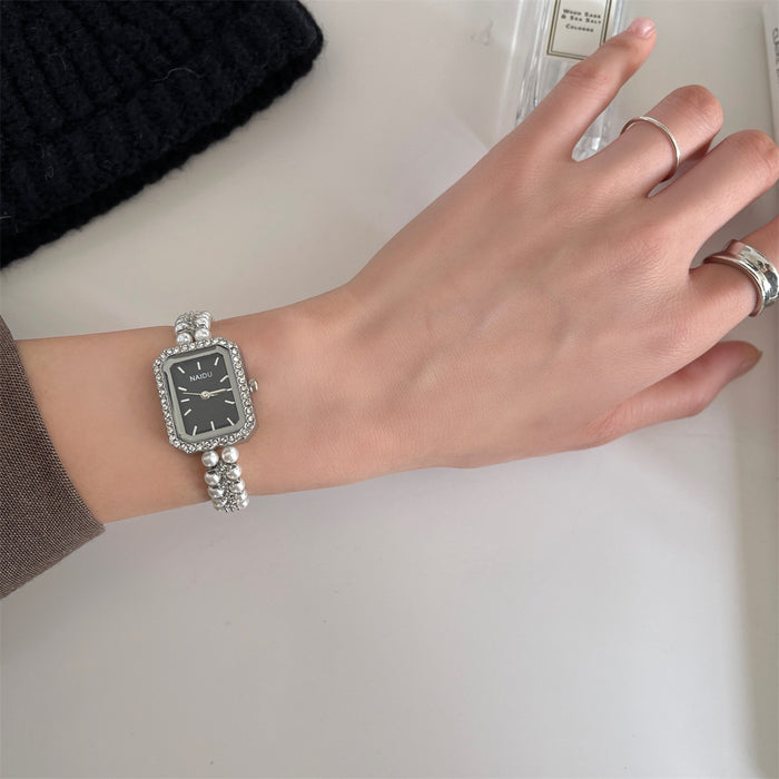 Hand wearing a silver watch with a plain background