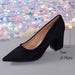 A single black pointed-toe high heel shoe shown on a gray surface with a colorful sequin backdrop. A measurement overlay indicates the heel height as 7cm (2.