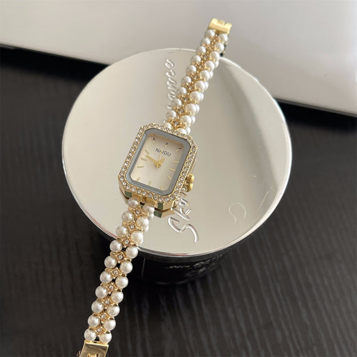 Pearl bracelet watch with gold accents on a white dish