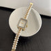 Pearl bracelet watch with gold accents on a white dish