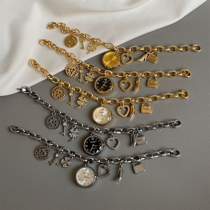 Three gold and silver charm bracelets on a gray surface with a white fabric background.
