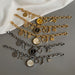 Three gold and silver charm bracelets on a gray surface with a white fabric background.