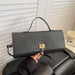 A black woven leather handbag with a top handle and gold-tone clasp, held by a hand in front of a white slatted door and black leather chair.