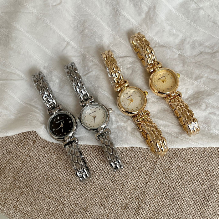 Four watches in silver, gold, and bronze on a textured fabric background