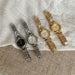 Four watches in silver, gold, and bronze on a textured fabric background