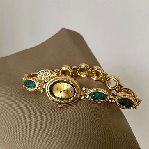 Gold bracelet with gemstone accents on a beige surface