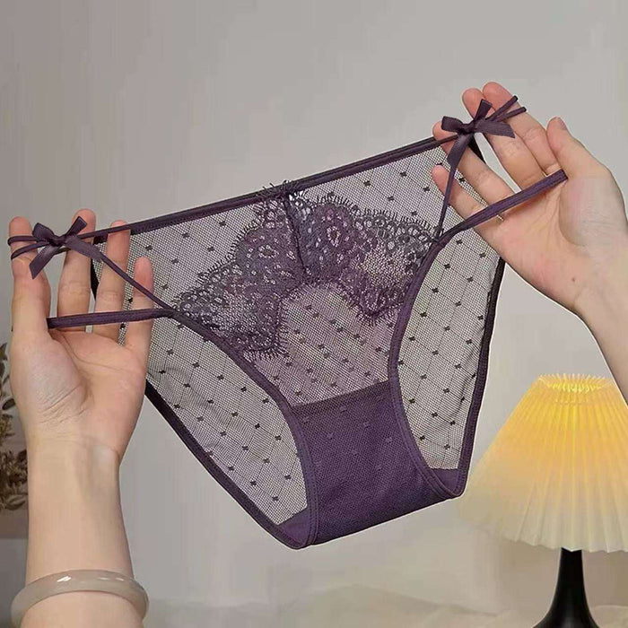 A pair of sheer purple lace and mesh panties with bow details on the sides, held up by two hands against a softly lit indoor background.