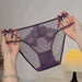 A pair of sheer purple lace and mesh panties with bow details on the sides, held up by two hands against a softly lit indoor background.