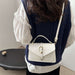 A person shown from the back wearing a navy cable-knit vest over a white blouse, carrying a small white top-handle handbag with a gold-tone clasp and shoulder strap.