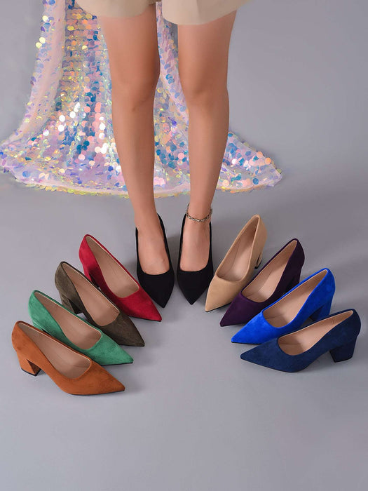 A set of women's pointed-toe high heels in multiple colors, displayed on a gray floor with a model's legs standing behind them. The shoes include black, red, olive green, brown, beige, purple, blue, and navy suede styles.