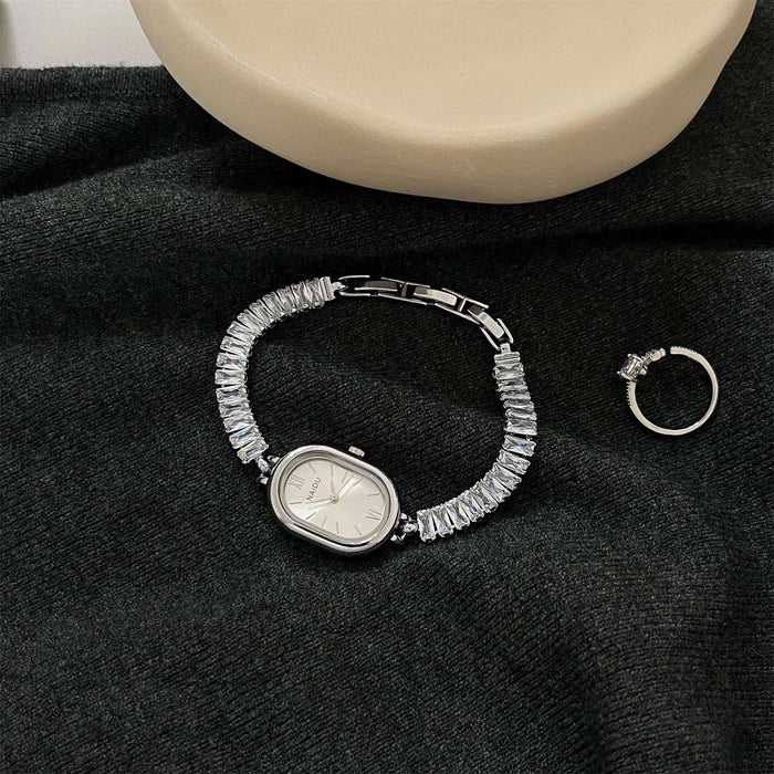 Silver bracelet with gemstones and a ring on a black fabric background