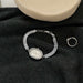 Silver bracelet with gemstones and a ring on a black fabric background