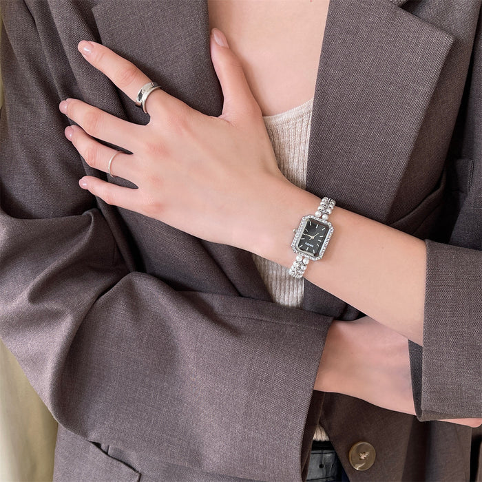 Person wearing a silver bracelet on a wrist with a brown coat