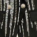 Black garment with silver embellishments and lion head buttons on a black background