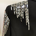 Black garment with metallic embellishments on a plain background