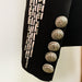 Black jacket with silver buttons and decorative elements on a light background