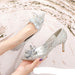 Silver glitter high heels with a decorative flower on a light background