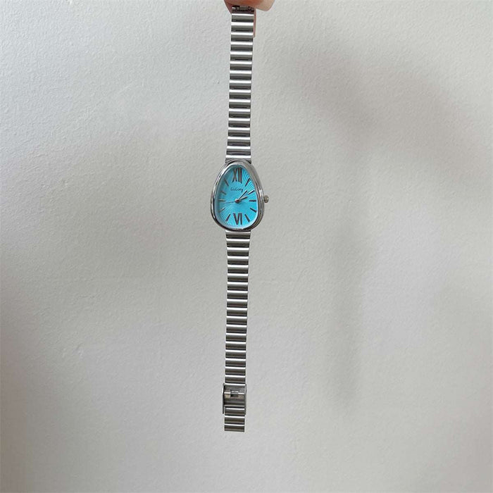 A vintage-style wristwatch with a silver-toned metal link bracelet and a bright turquoise blue oval dial, held by a hand against a plain off-white wall.