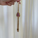 Gold wristwatch held by a hand against a white curtain background