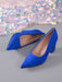 A pair of bright royal blue suede pointed-toe pumps with block heels, displayed on a gray surface with a shimmering sequin fabric in the background.