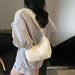 A woman wearing an oversized light gray textured sweatshirt and shorts, shown from the back while carrying a cream-colored shoulder bag.