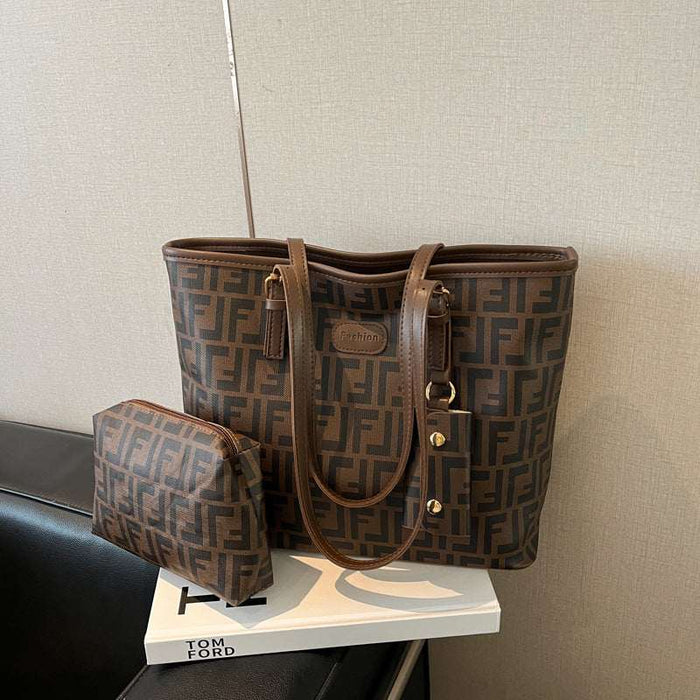 A brown Fendi tote bag with the signature FF monogram pattern and a matching zip pouch, displayed on a white book on a black leather chair against a beige wall.