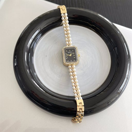 Gold and pearl watch on a black dish