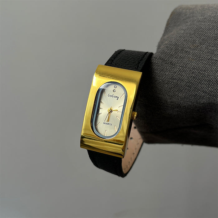 Gold wristwatch with black strap on a gray background