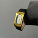 Gold wristwatch with black strap on a gray background