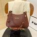 A brown leather handbag with knotted leather handles and gold-tone hardware, displayed on a black chair in front of a white draped fabric backdrop.