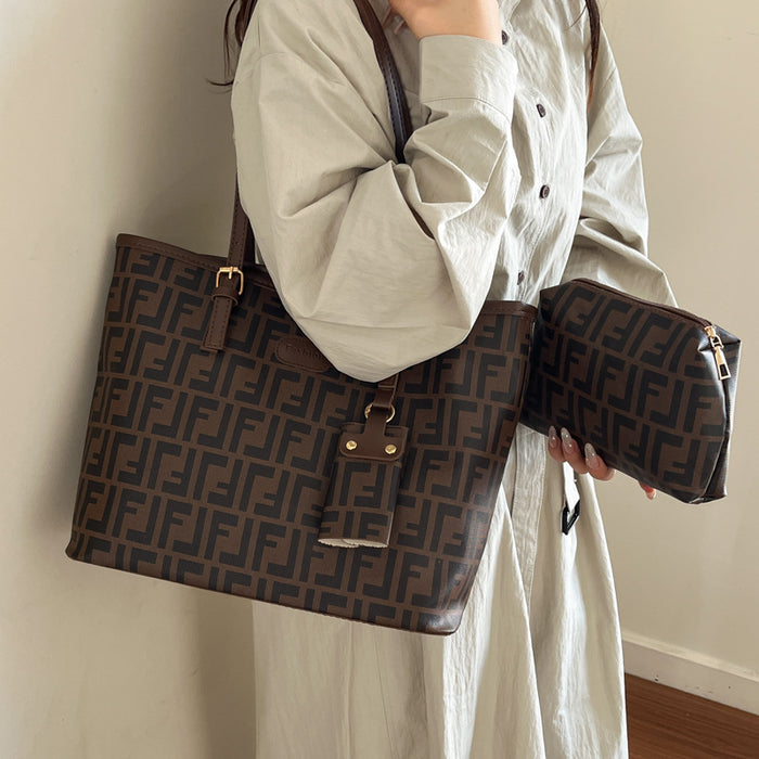 A person wearing a light beige shirt and skirt holds a large brown monogram tote bag and a matching zip pouch. The bags feature the signature Fendi FF logo pattern in dark brown on a medium brown background, with gold-tone hardware.