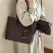 A person wearing a light beige shirt and skirt holds a large brown monogram tote bag and a matching zip pouch. The bags feature the signature Fendi FF logo pattern in dark brown on a medium brown background, with gold-tone hardware.
