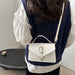 A person shown from the back wearing a navy cable-knit vest over a white blouse, carrying a small white top-handle handbag with a gold-tone clasp and shoulder strap.