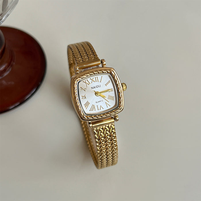 Gold watch with a white face on a light background