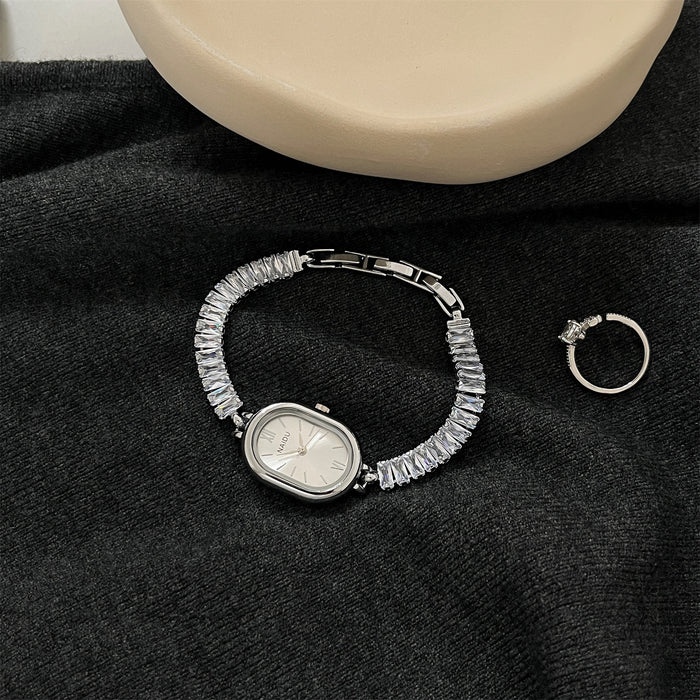 Silver bracelet with gemstones and a ring on a black fabric background