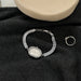 Silver bracelet with gemstones and a ring on a black fabric background