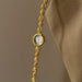 Gold bracelet watch with a white face on a beige background