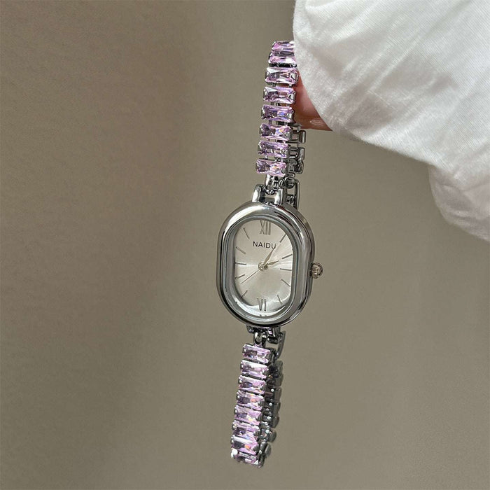 Silver watch with pink gemstone bracelet held by a hand against a neutral background