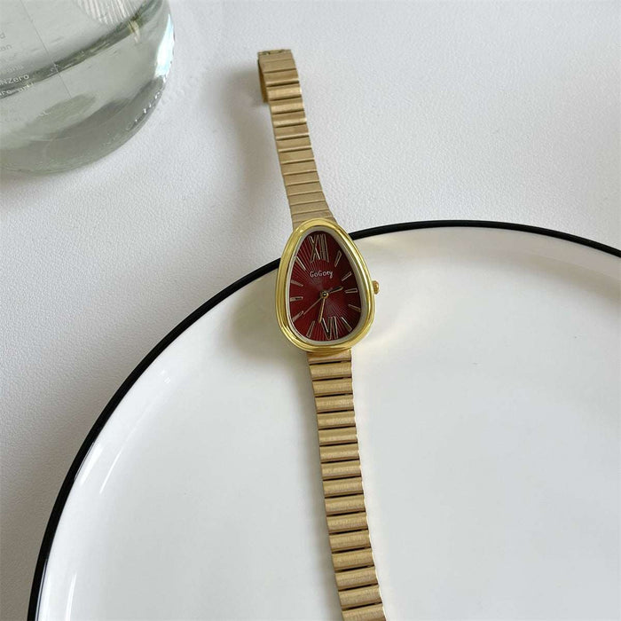 Gold watch with a red face on a white surface