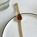 Gold watch with a red face on a white surface